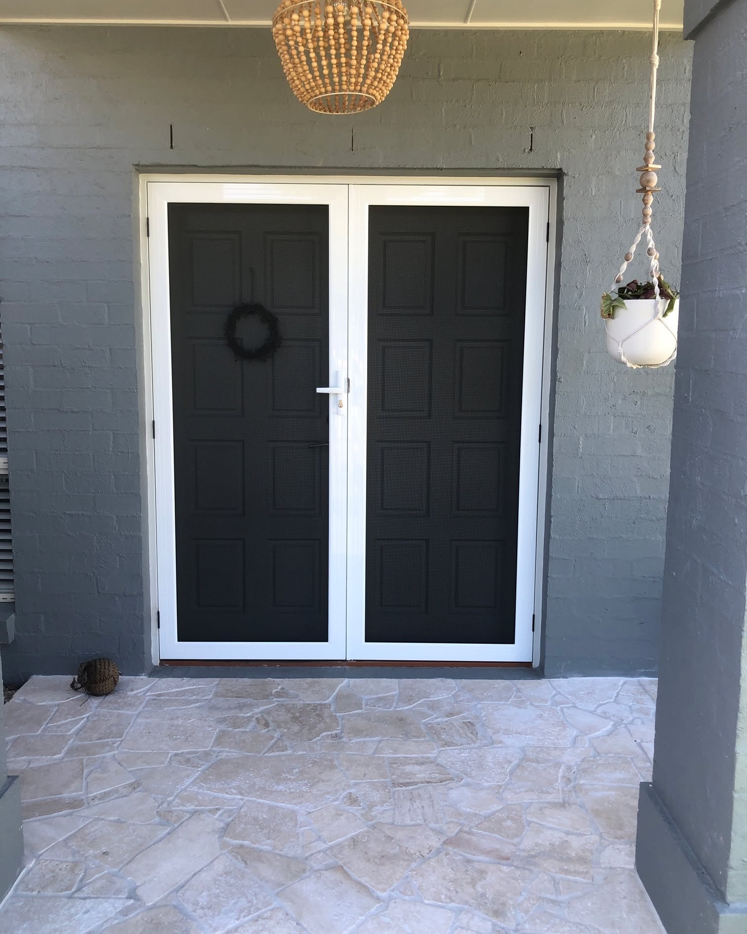 Double ornate hinged security doors on painted brick home