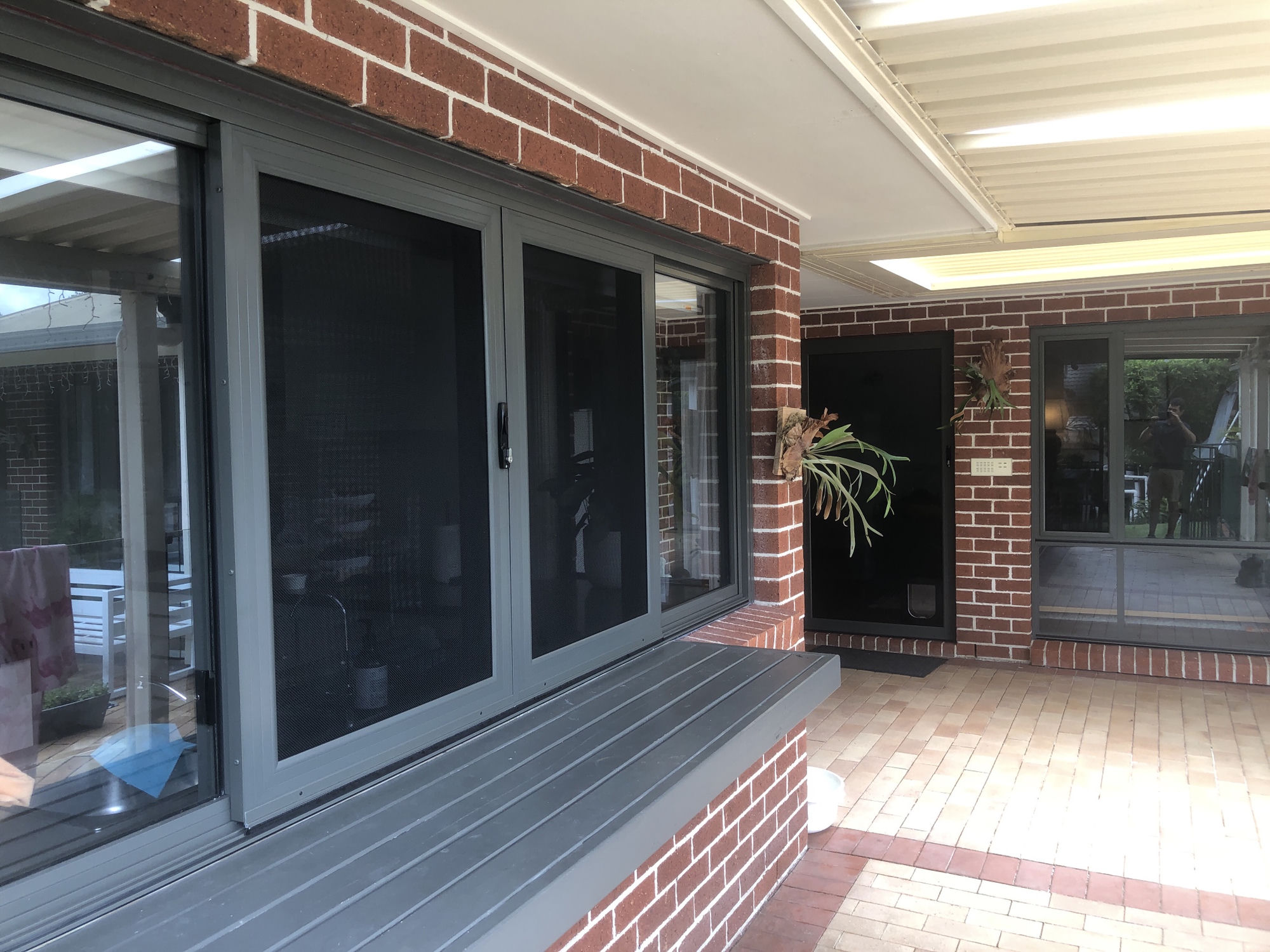Dark-frame sliding security screens on brick alfresco